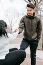 Asian man giving hand to fell female friend