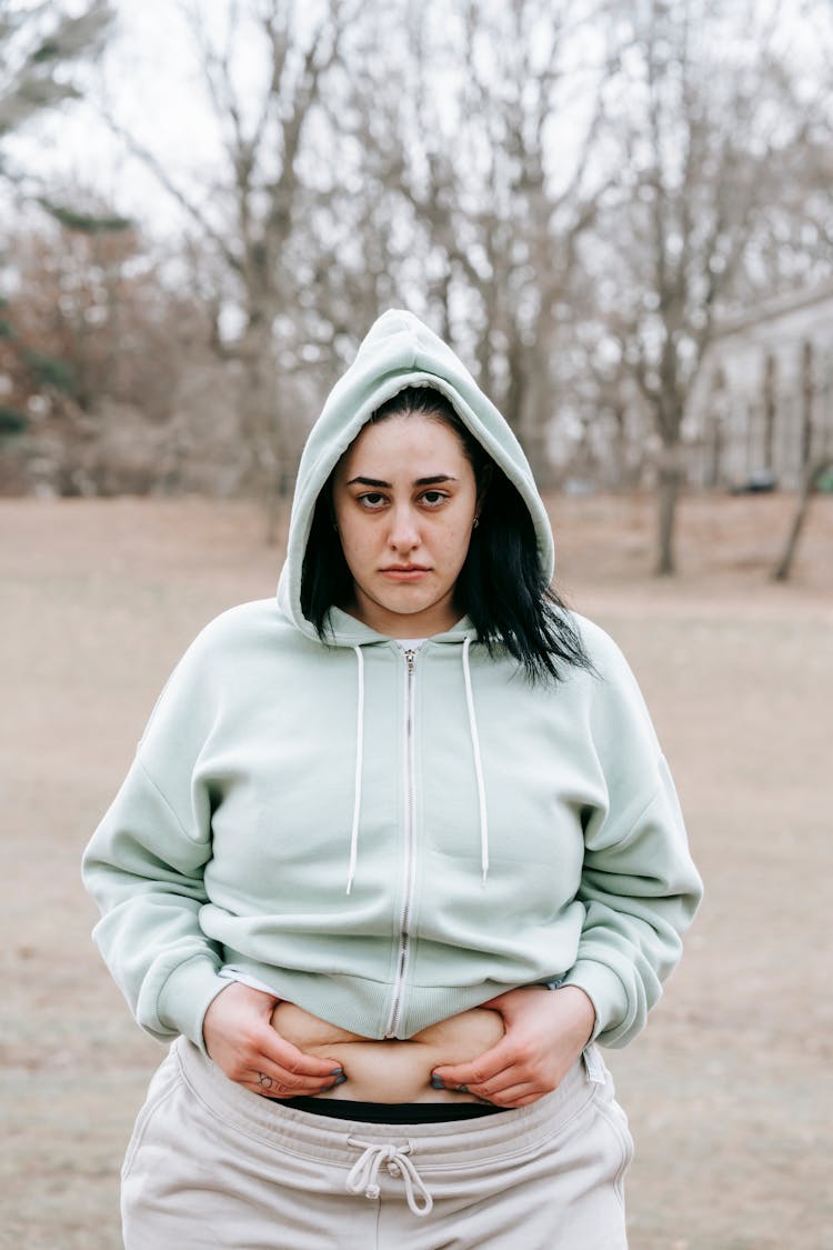 Upset Woman Touching Plump Belly In Autumn Park