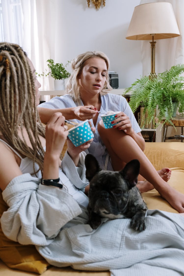 Women In Pajamas Sitting On The Couch While Eating Sundae