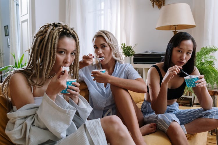 A Group Of Friends Sitting On The Couch While Eating Ice Cream