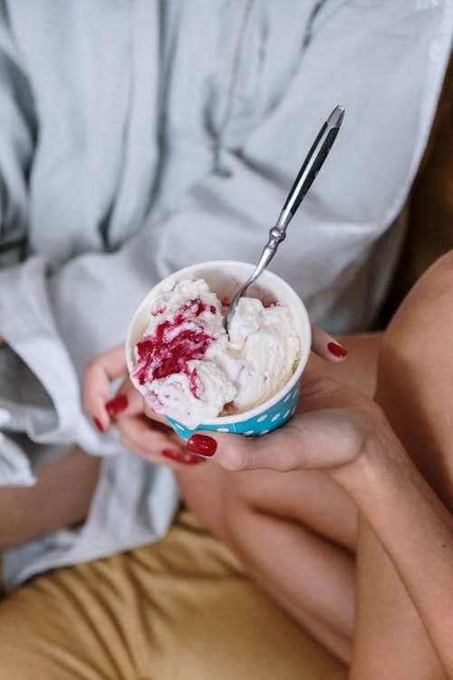 A Person Holding an Ice Cream on a Paper Cup with Spoon