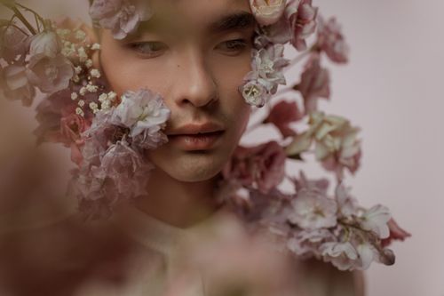 Free A delicate portrait of a man surrounded by pastel flowers, exuding beauty and serenity. Stock Photo