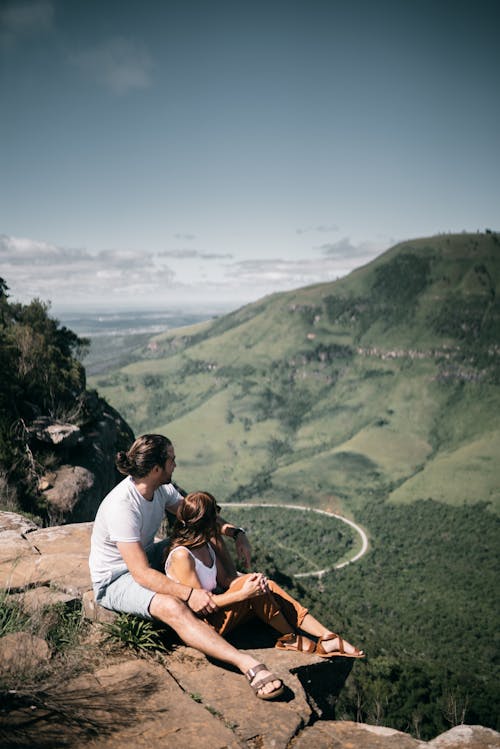 Free Man and Woman Sitting on a Mountain Cliff Stock Photo