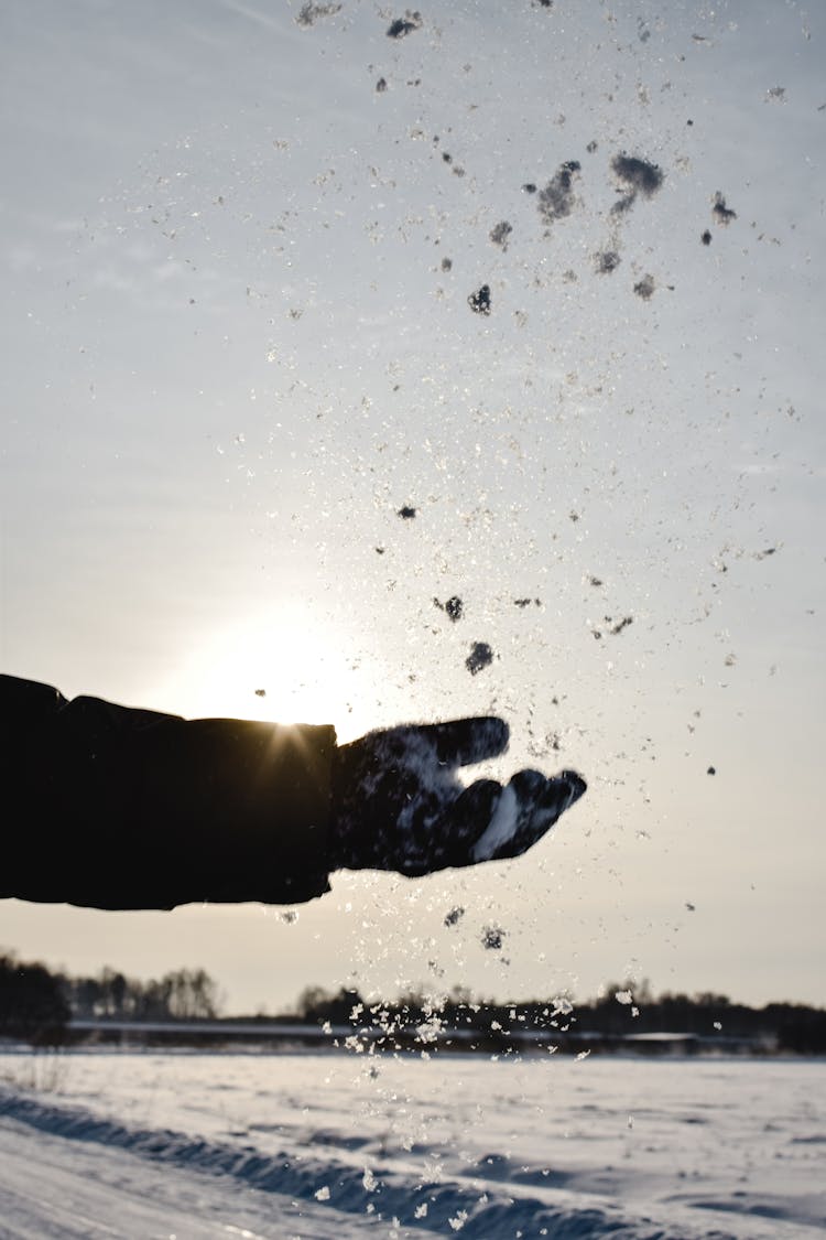 A Hand Throwing The Snow In The Air