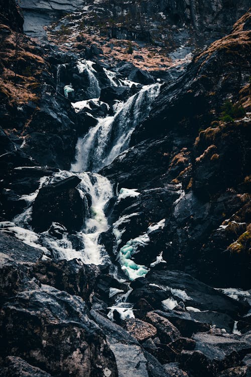 Waterfall flowing through rocky mountains with moss