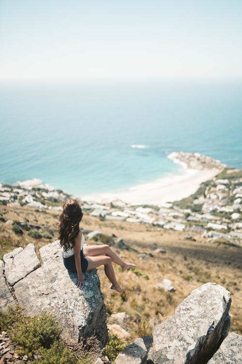 Free A Woman Sitting on the Rock while Looking at the Beautiful View Stock Photo