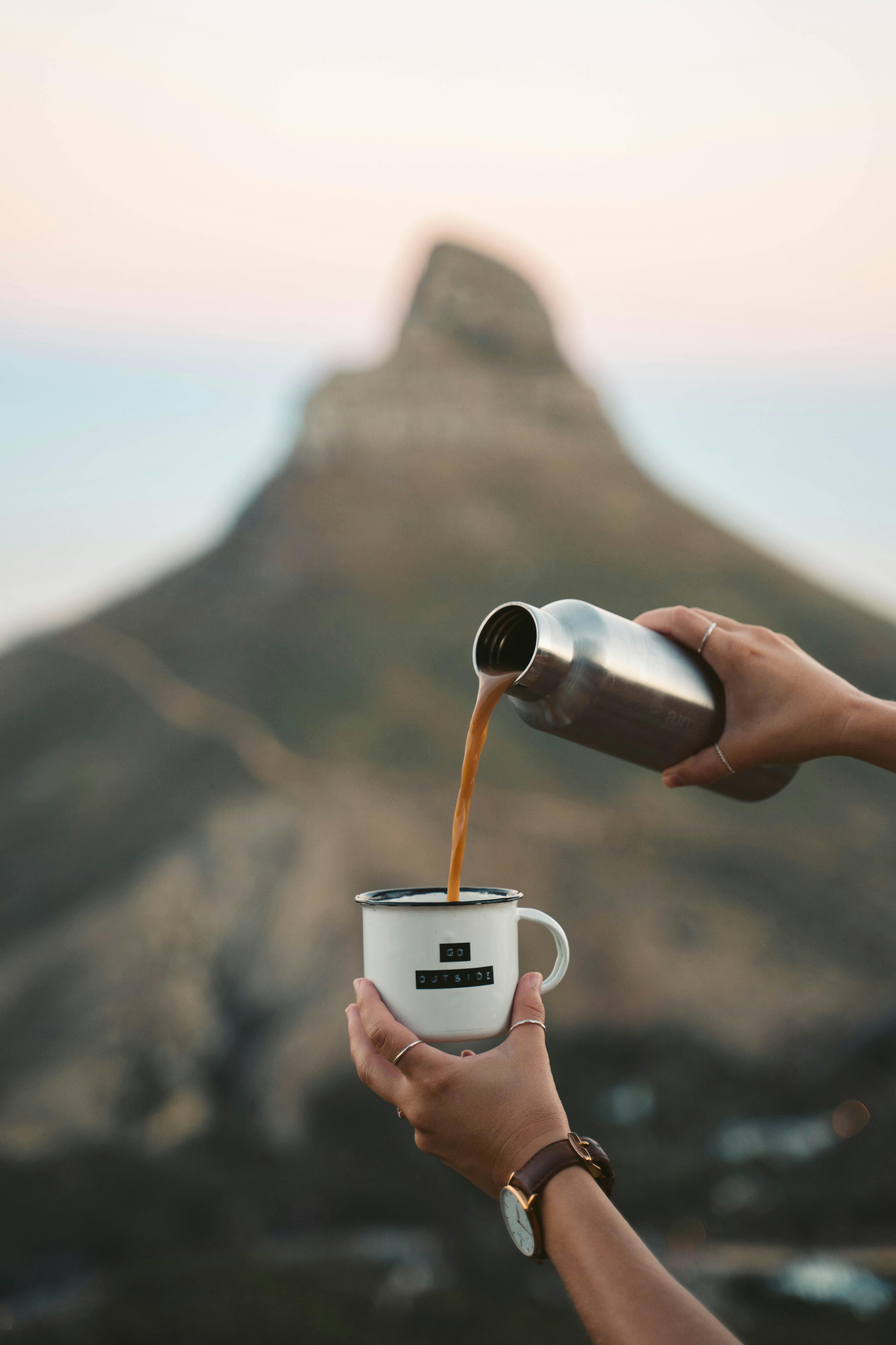 Coffee being poured from a flask into a cup with Lion's Head Mountain backdrop.