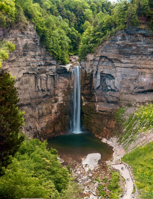 Free Stunning waterfall cascading into a calm pool surrounded by vibrant greenery and towering cliffs. Stock Photo