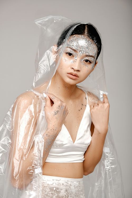 Free Elegant portrait of a woman with glitter makeup and clear raincoat in a studio setting. Stock Photo
