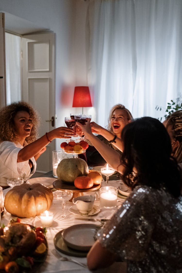 Women Sitting By The Table Holding Wine Glasses