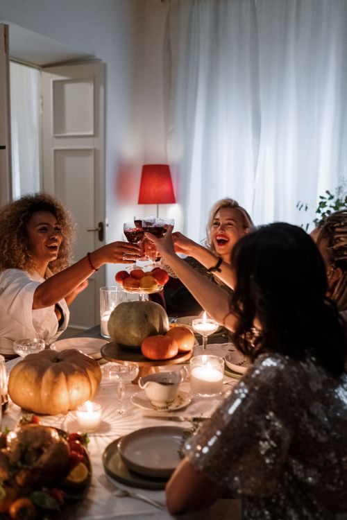 Free A joyous gathering of diverse friends celebrating around a candle-lit dinner table, toasting with wine glasses. Stock Photo