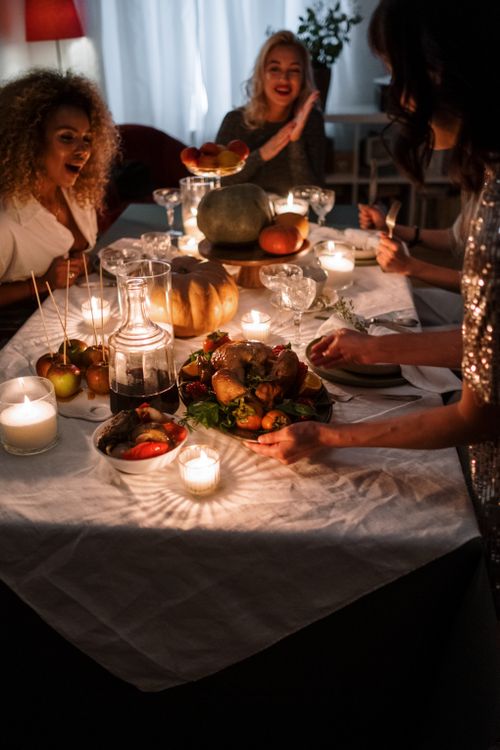 Free Charming indoor dinner scene with friends celebrating with food, candles, and togetherness. Stock Photo