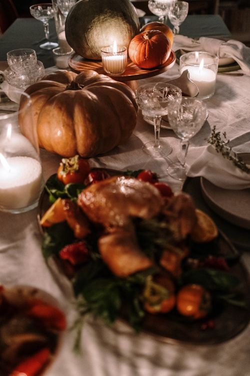 Free A beautifully arranged Thanksgiving dinner table with turkey, pumpkins, and candles creating a warm atmosphere. Stock Photo
