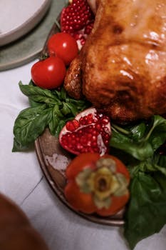 Close-up of a roasted turkey with fresh tomatoes, basil, and pomegranate on a plate.