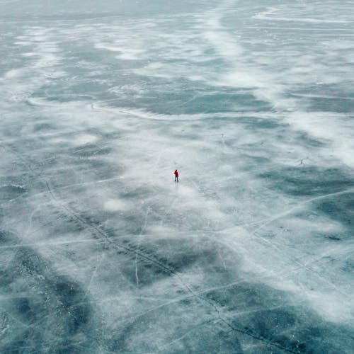 Aerial Photography of a Man Walking on a Frozen Lake 