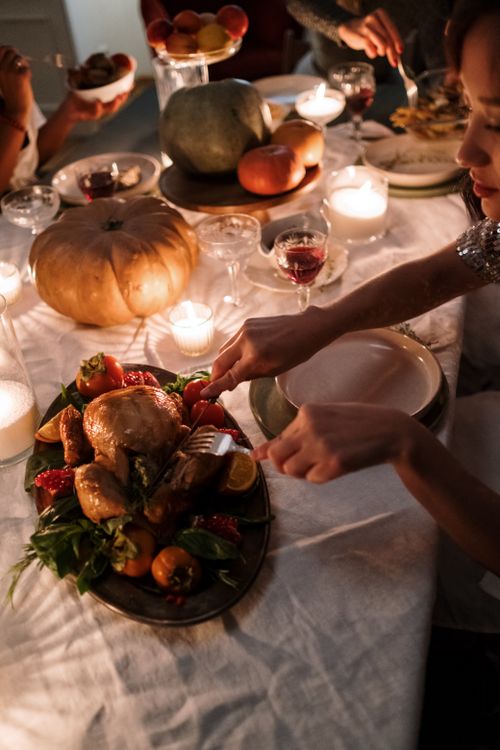 Free Warm Thanksgiving dinner setting featuring roast turkey, candles, and festive table decorations. Stock Photo