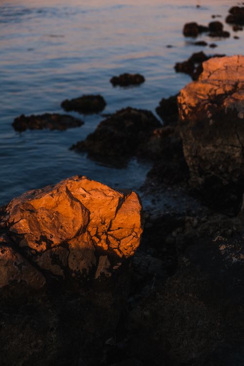 Free Beautiful rocky shore with ocean waves during sunset, highlighting natural textures and colors. Stock Photo