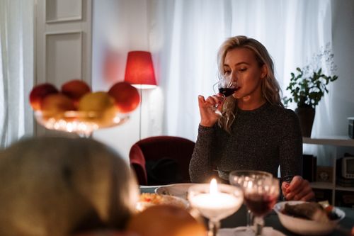 Free Woman savoring red wine in a cozy indoor dining setting with candlelight ambiance. Stock Photo