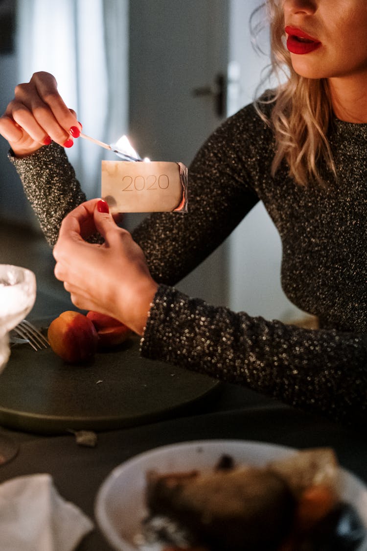 Close-Up Photo Of A Woman Burning A 2020 Card