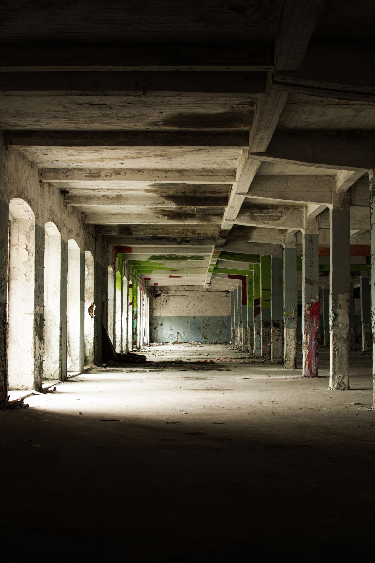 An abandoned warehouse interior with haunting pillars and a shadowy atmosphere, recalling the empty halls of Hashima