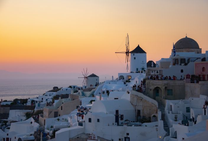 Experience the stunning sunset in Santorini, Greece, showcasing iconic white architecture and windmills.