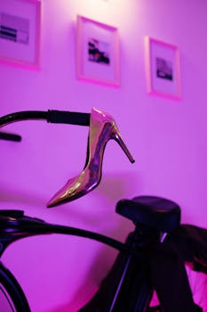 Artistic display of a high heel shoe on a bicycle with a vibrant purple background.