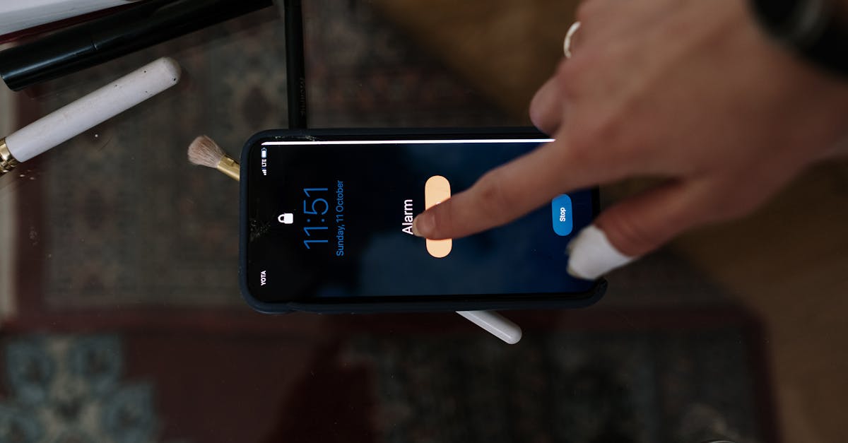 Close-up of a person touching a smartphone alarm screen with makeup items nearby. Close-up of a person touching a smartphone alarm screen with makeup items nearby.