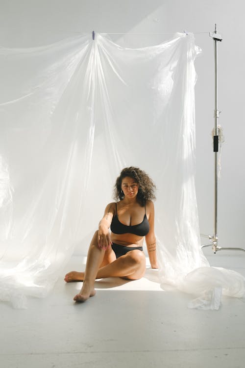 A Woman in her Underwear Sitting on the Floor Beside Plastic Curtains