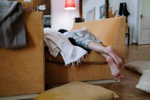 Free A Person Lying on Front on a Brown Sofa Stock Photo