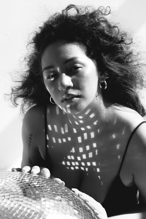 Grayscale Photo of a Woman Posing with a Disco Ball