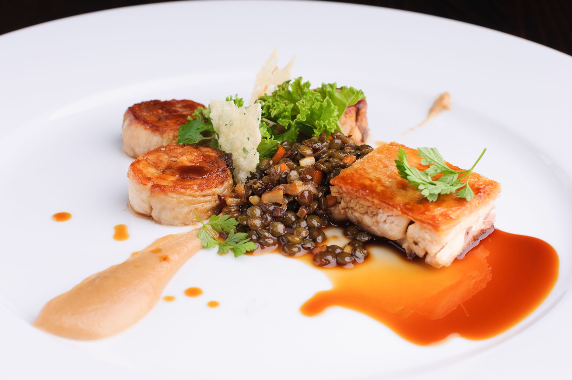Elegantly plated fish dish with lentils and greens, showcasing modern culinary artistry.