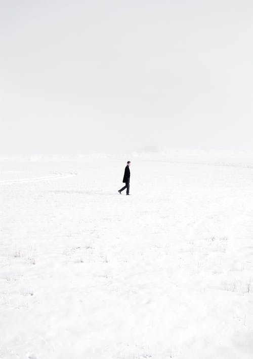 黑大衣的人在积雪覆盖的田野上行走