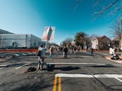 Anonymous dissidents with inscriptions on placard on asphalt roadway between houses under blue sky in city