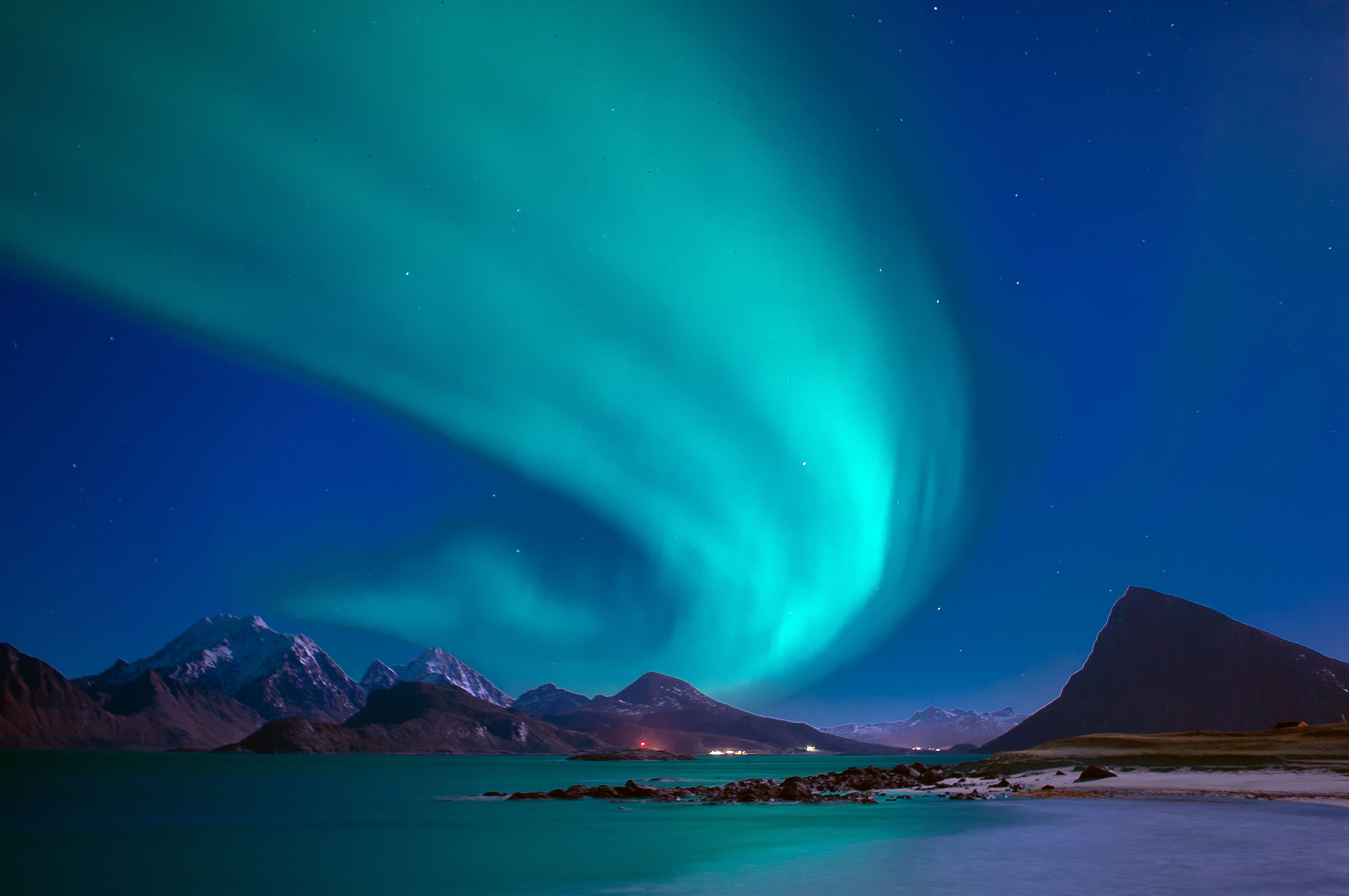 A breathtaking display of the aurora borealis over snow-capped mountains and calm sea at night. A breathtaking display of the aurora borealis over snow-capped mountains and calm sea at night.