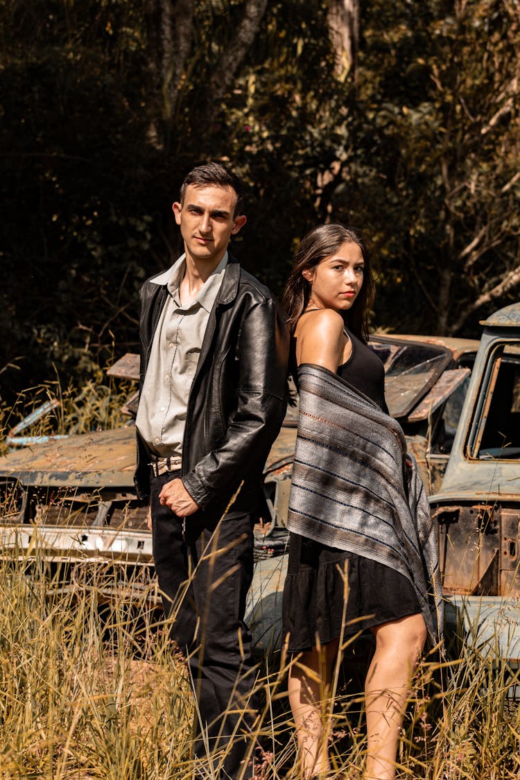 A Couple Posing In Front Of Broken Cars