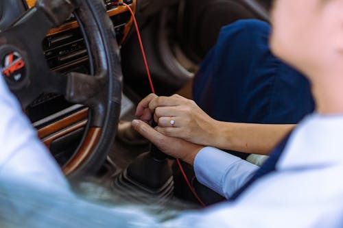 Free A Couple Holding Hands on a Stick Shift in a Car Stock Photo