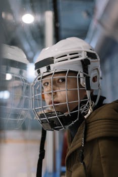Close-up portrait of a young ice hockey player wearing protective gear and helmet indoors.