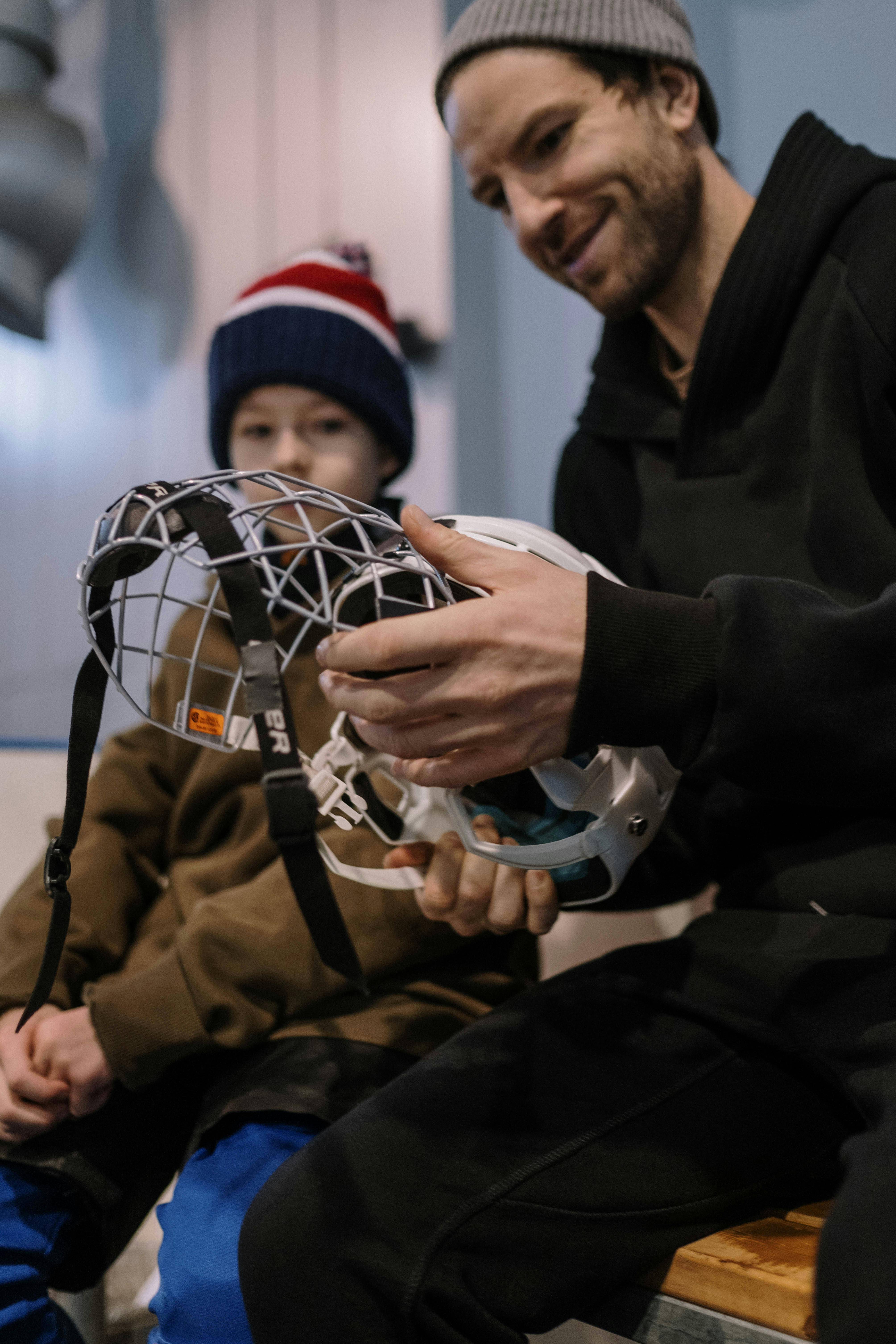 a man sitting beside a boy holding a hockey helmet