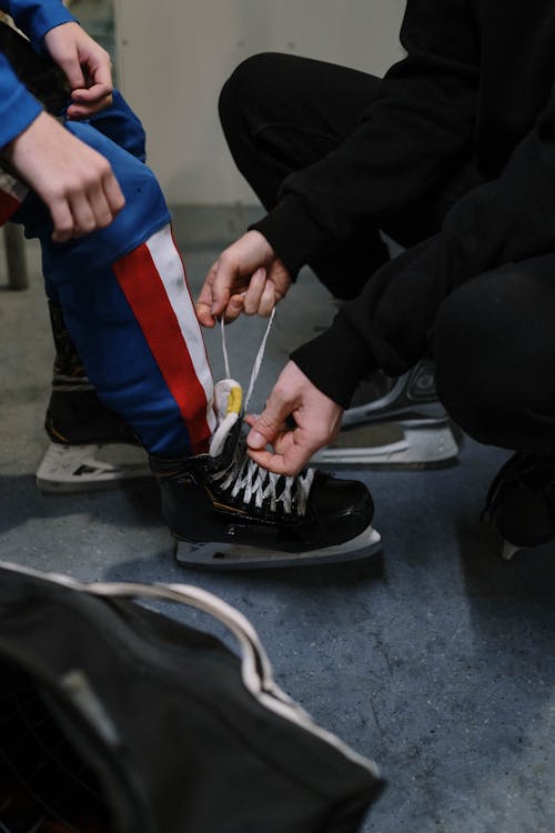 Woman Tying Shoelaces of Skates on her Childs Feet 