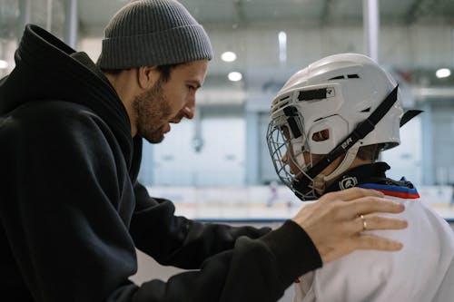 Boy in Ice Skating Clothing and his Father Talking before the Game 