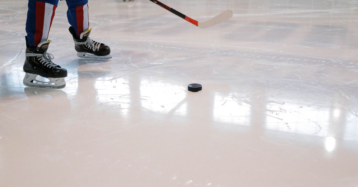 Dynamic shot of a hockey player maneuvering with stick and puck on ice rink.