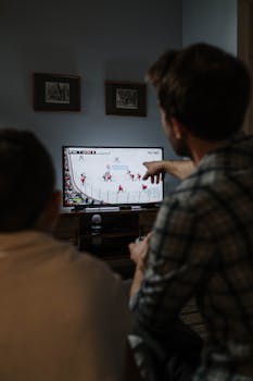 Father and son playing ice hockey video game together at home, fostering family bonding.