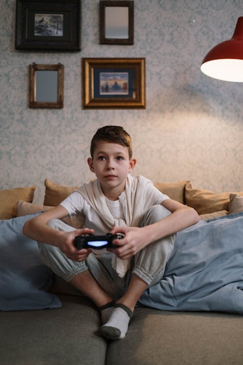 A Boy Playing Video Games while Sitting on the Sofa