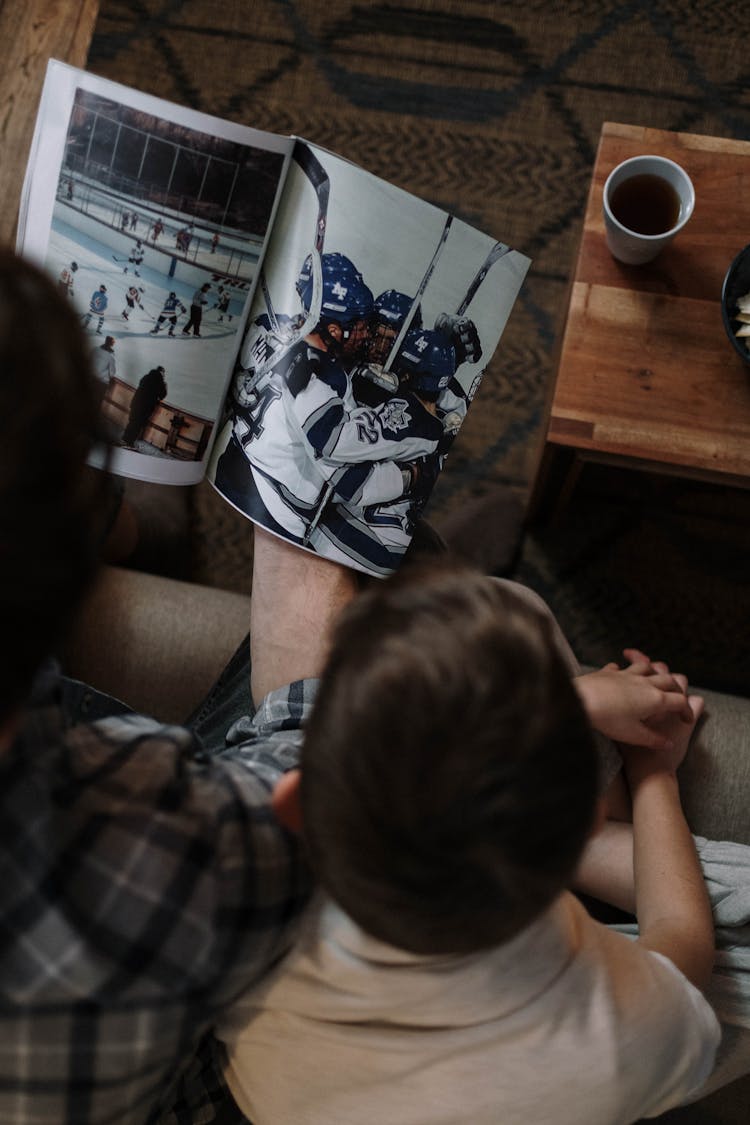 Father And Son Sitting With Ice Hockey Magazine