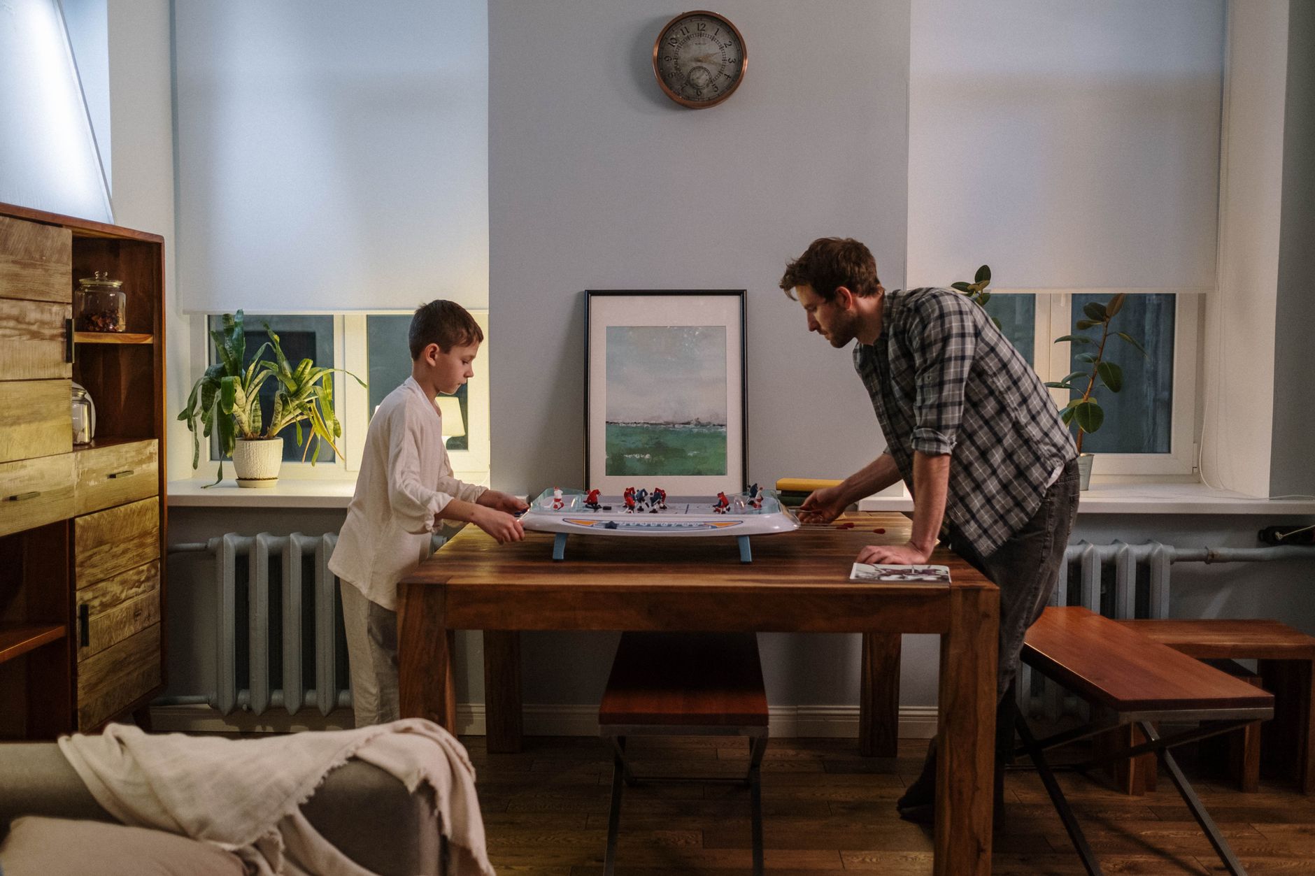 Father and son enjoy a game of table hockey together in a cozy living room setting.