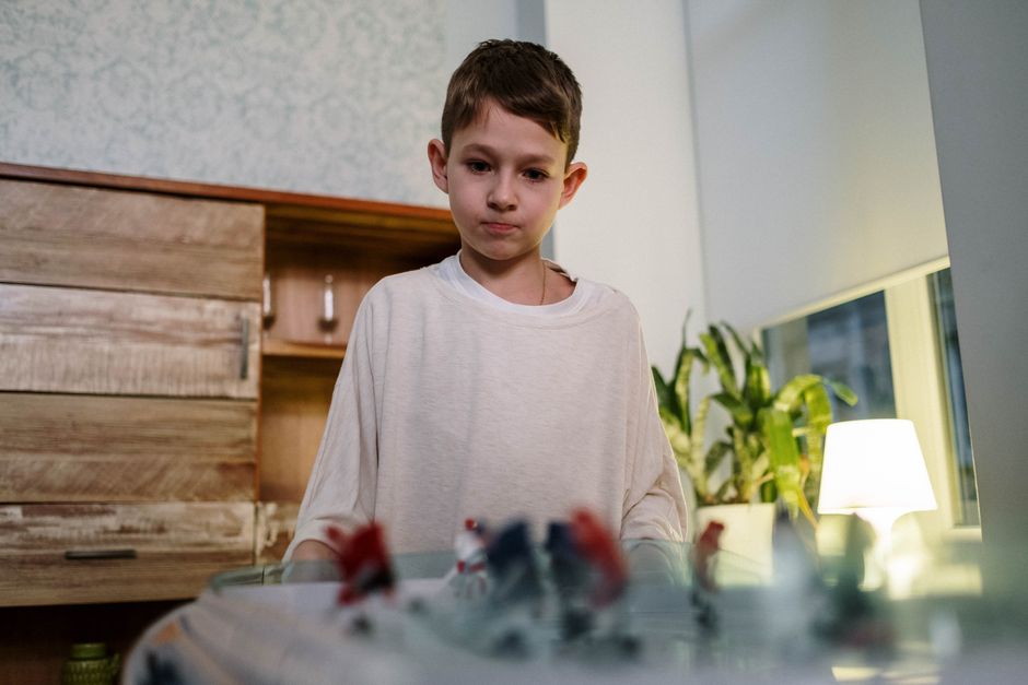 A young boy intensely playing table hockey indoors, showcasing fun and concentration.