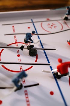 Detailed view of a tabletop hockey game showcasing player figurines and puck on a simulated ice rink.