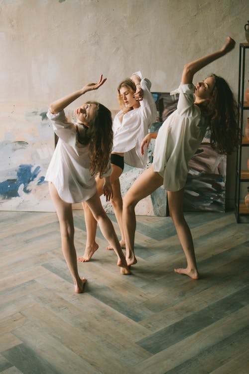 Female friends wearing shirts while dancing in studio