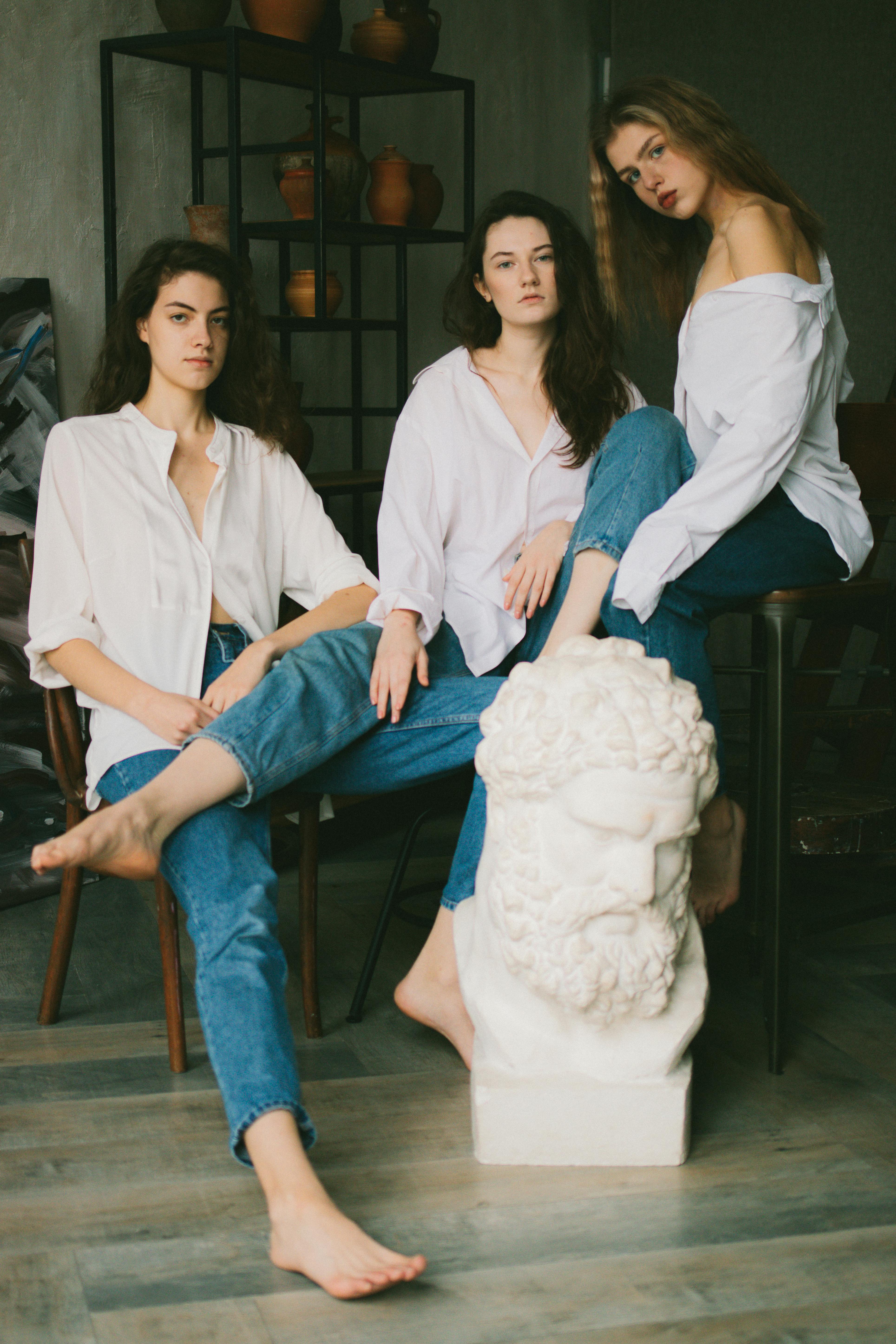 alluring young women in similar outfits resting in art studio