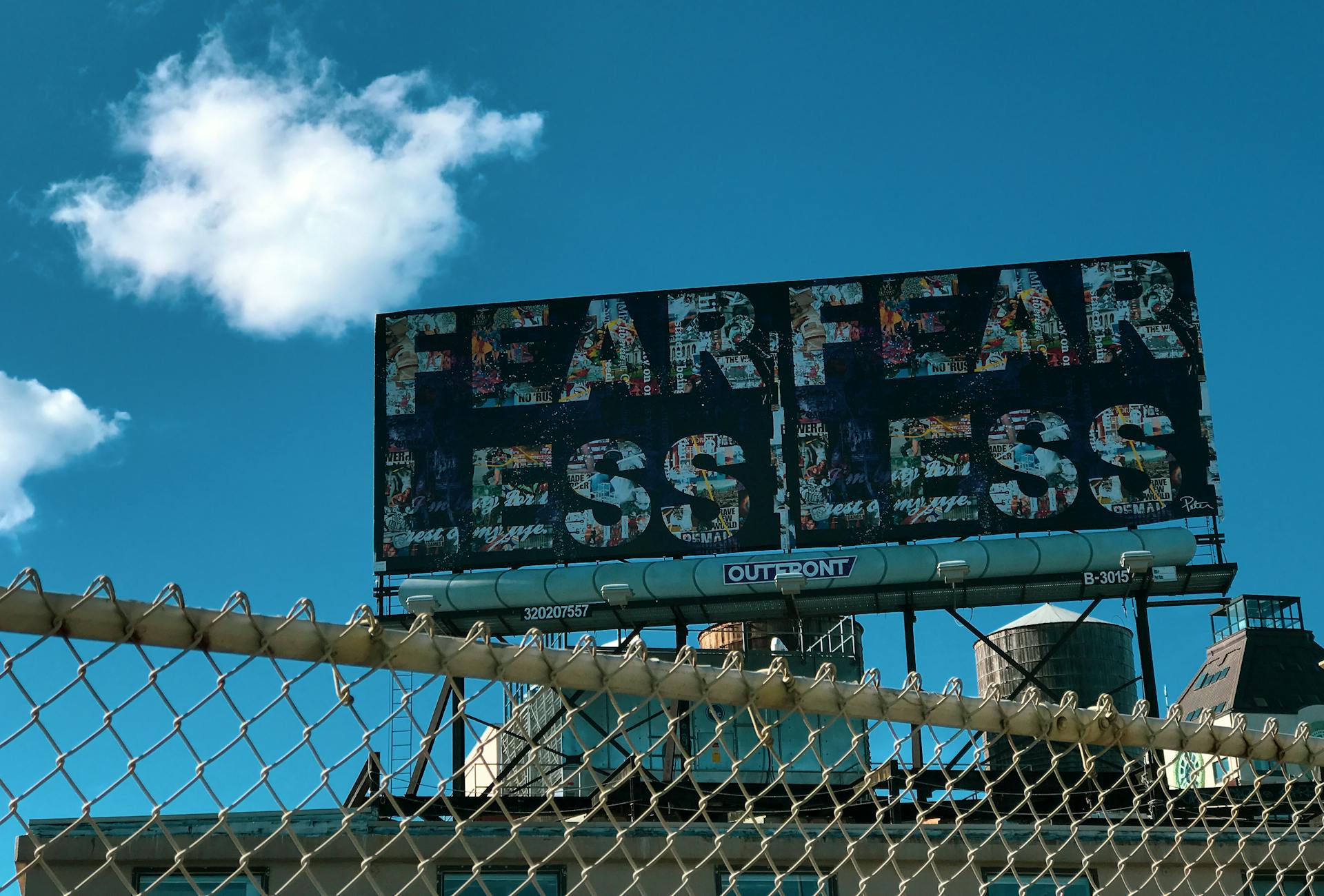 A bold 'Fearless' billboard against a clear blue sky in New York City.